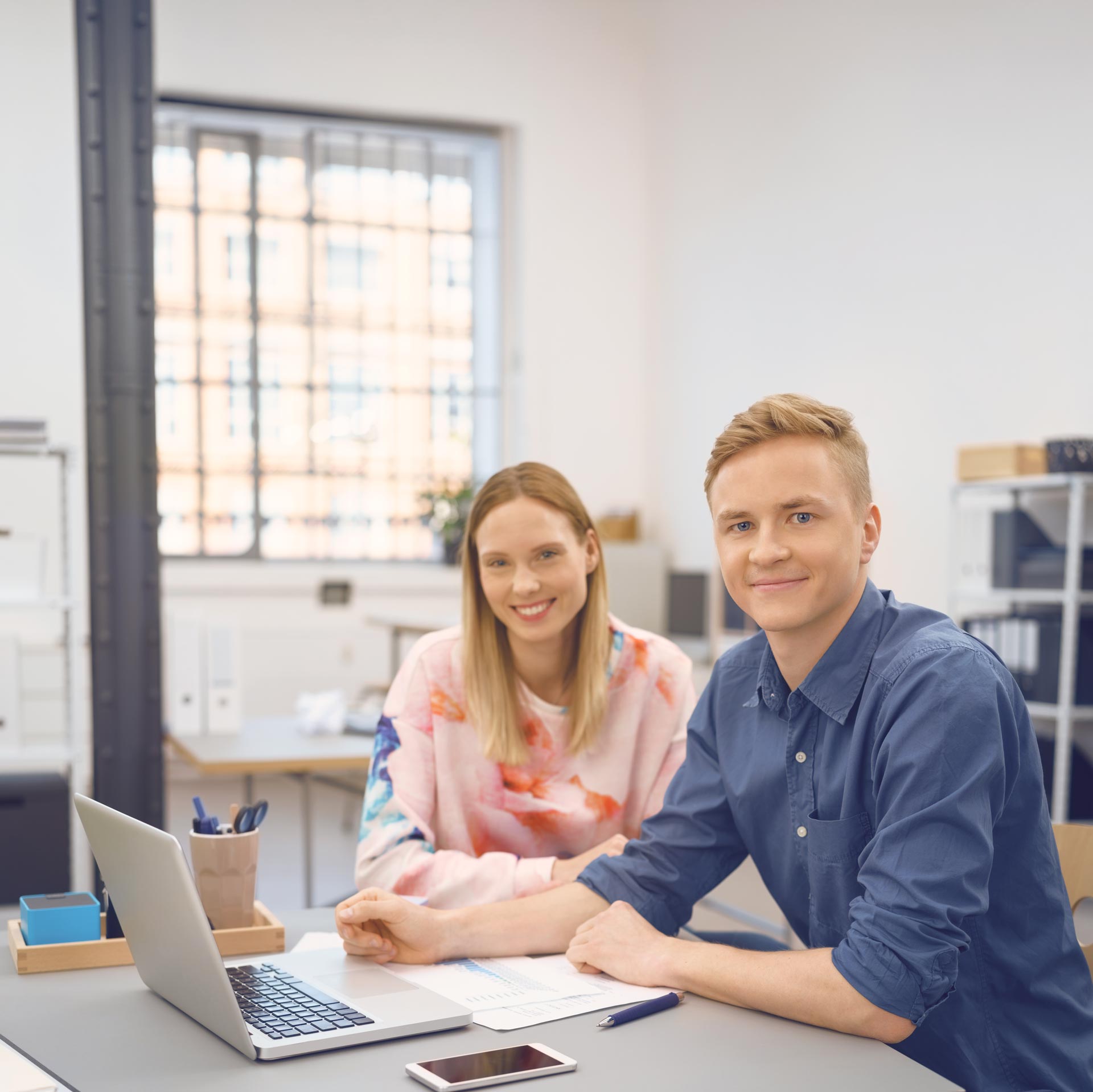 Zwei junge Menschen am Schreibtisch in einem Büro.